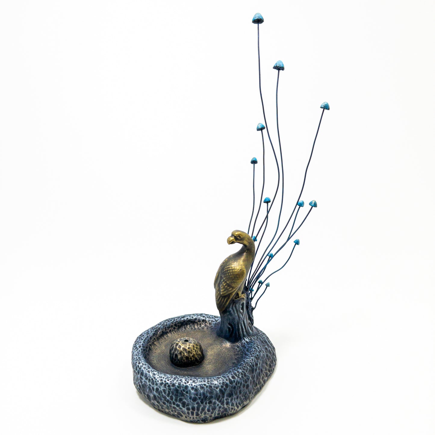 Decorative sculpture of a bird perched on a branch with a small pond on a white background
