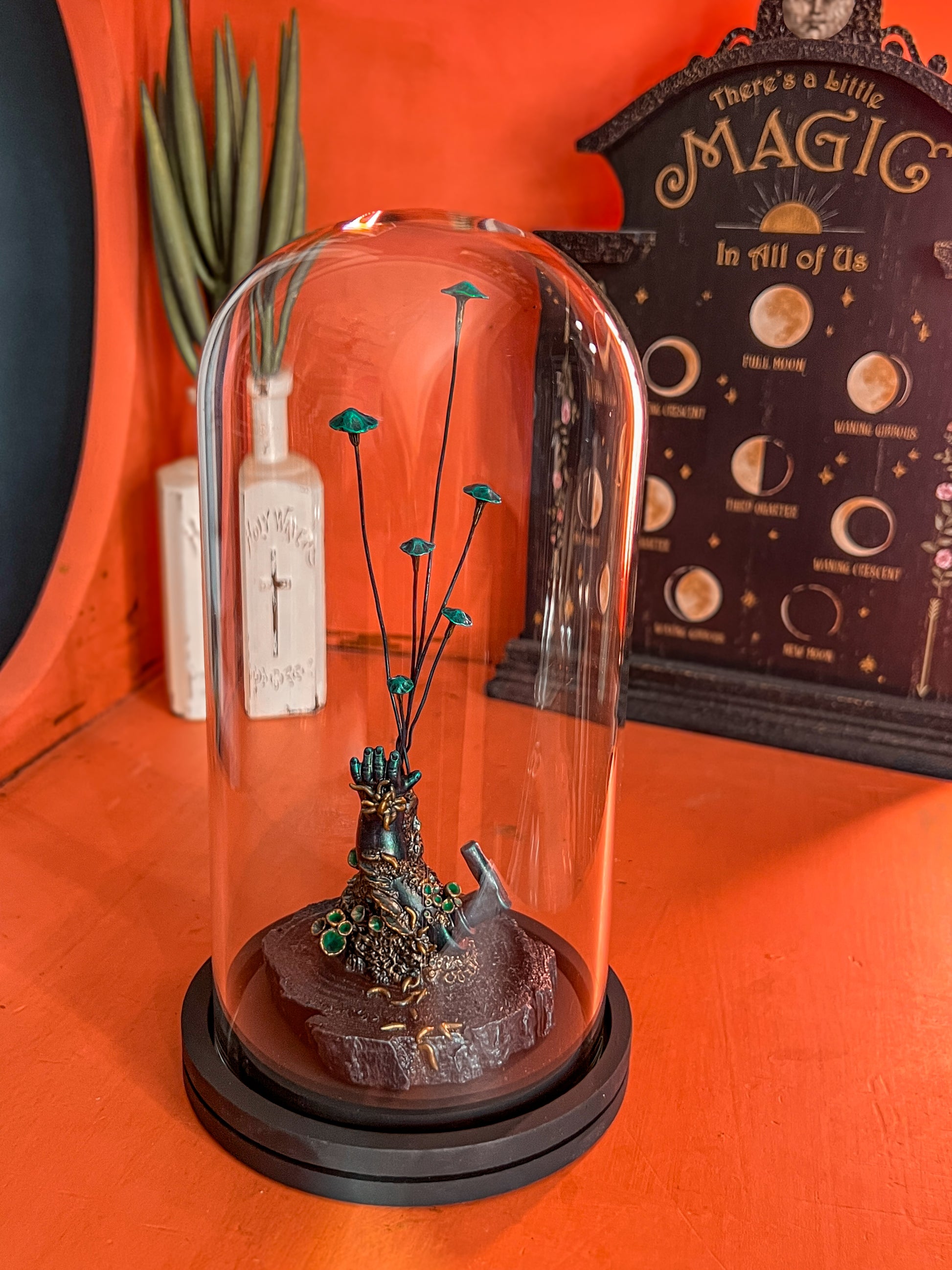 Fungi-covered vintage doll hand sculpture inside a glass dome – Metallic Spores series.