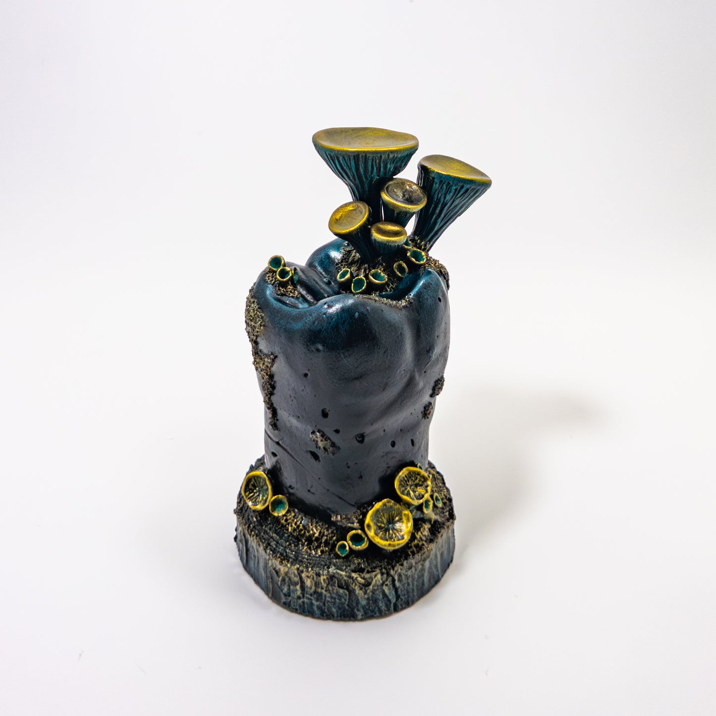 Teal fungi sculpture inside a glass cloche dome on a vintage dental model tooth.